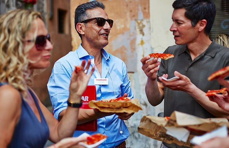 Travel Director sampling pizza with group.